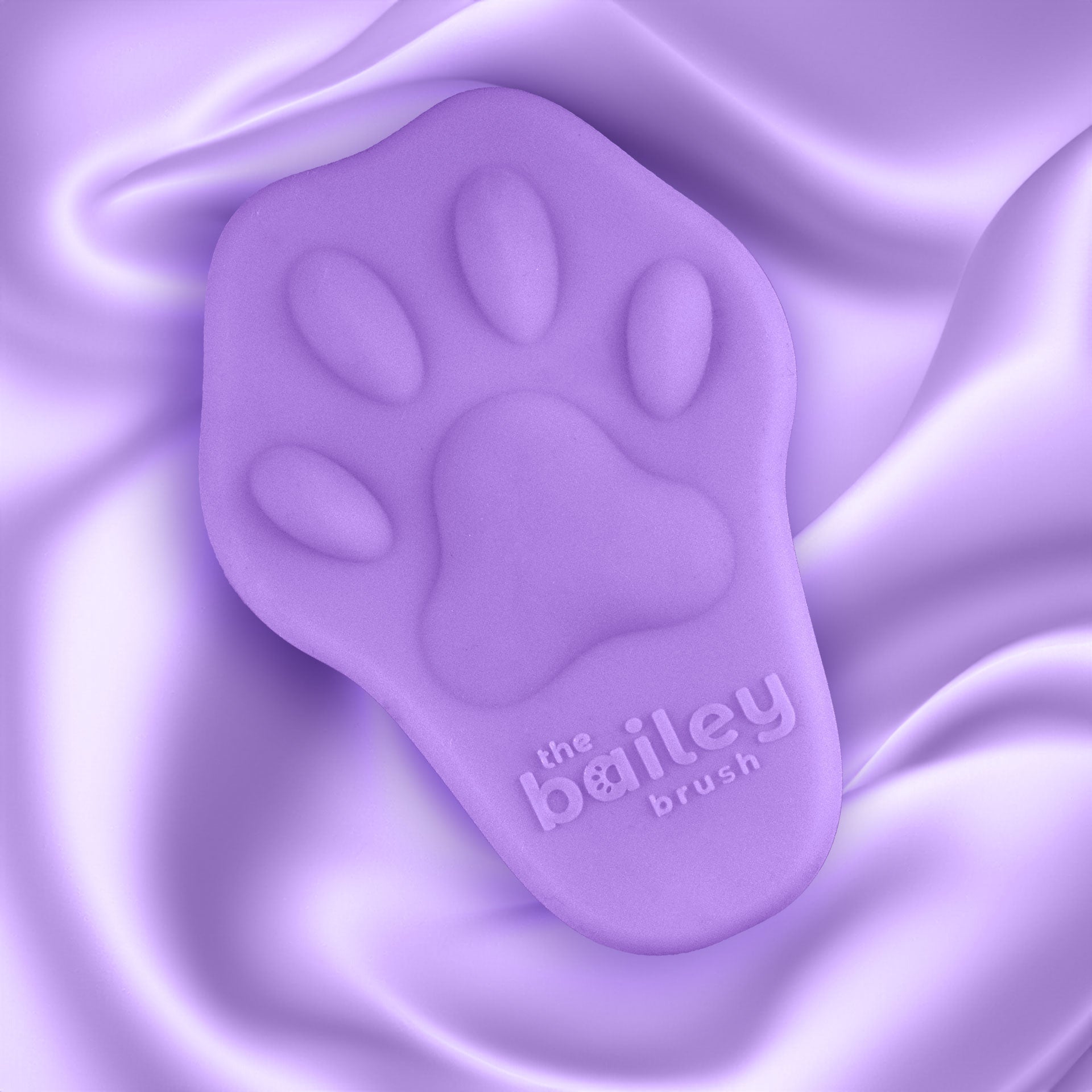 Purple paw-shaped brush with 'the bailey brush' branding on a purple fabric background