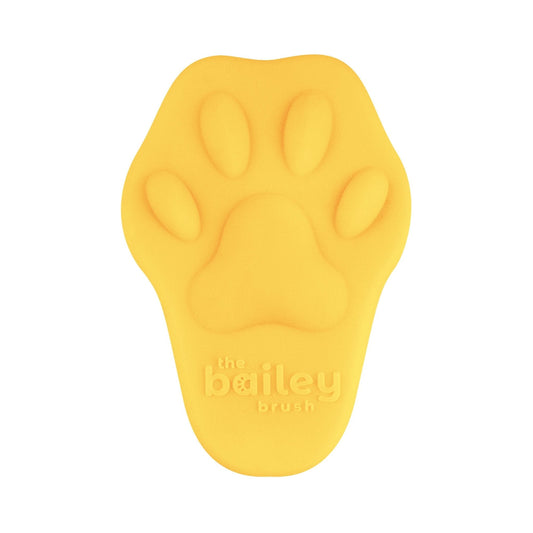 Yellow paw-shaped brush with 'the bailey brush' branding on a white background