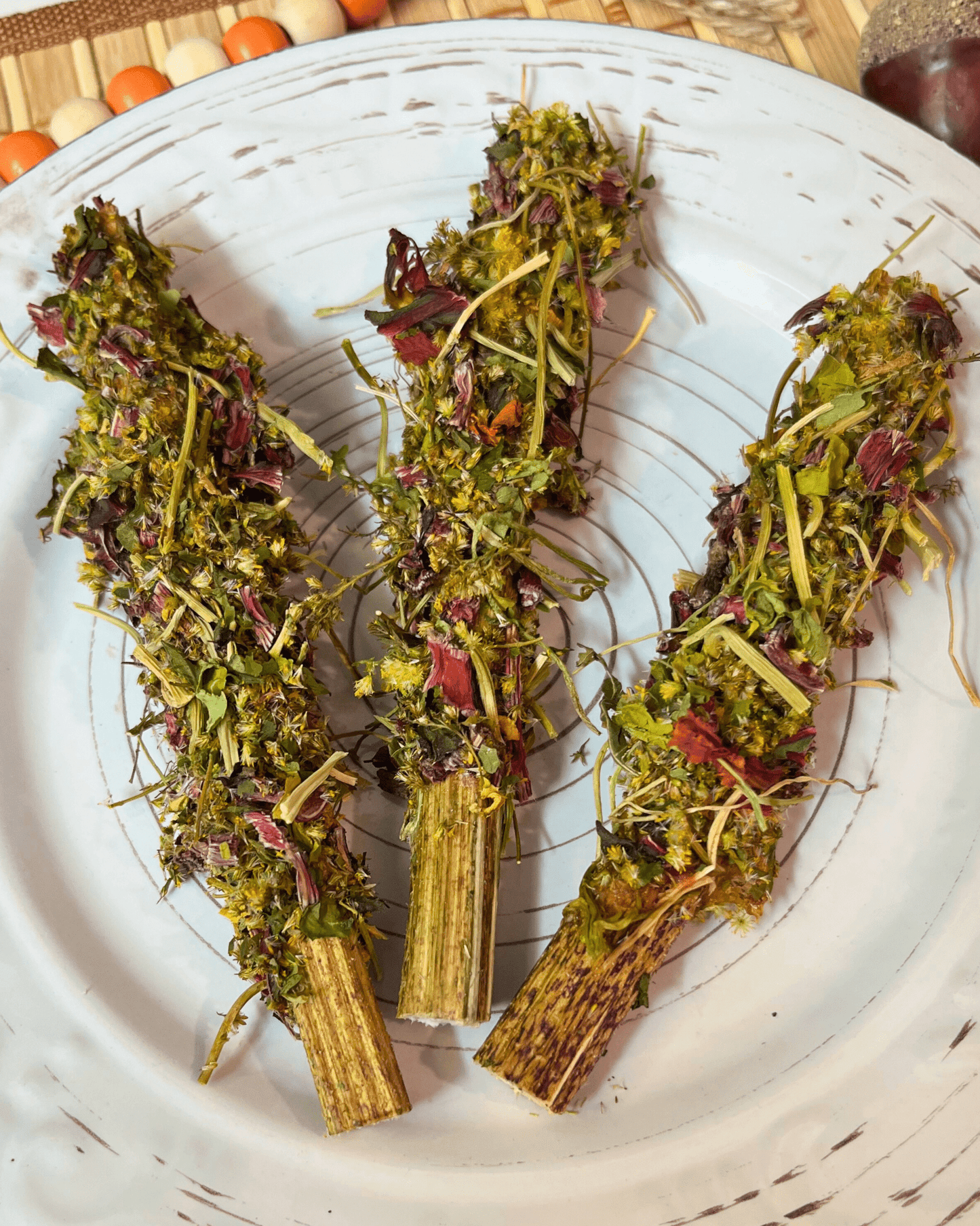 Three dried herb bundles on a white plate with a wooden surface in the background
