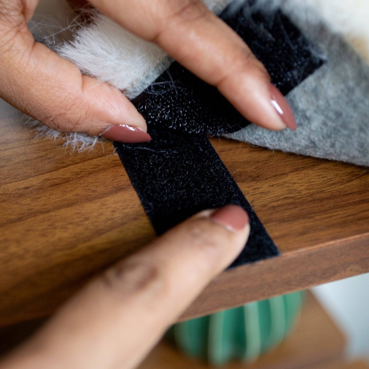 Person applying black double-sided tape to a wooden surface