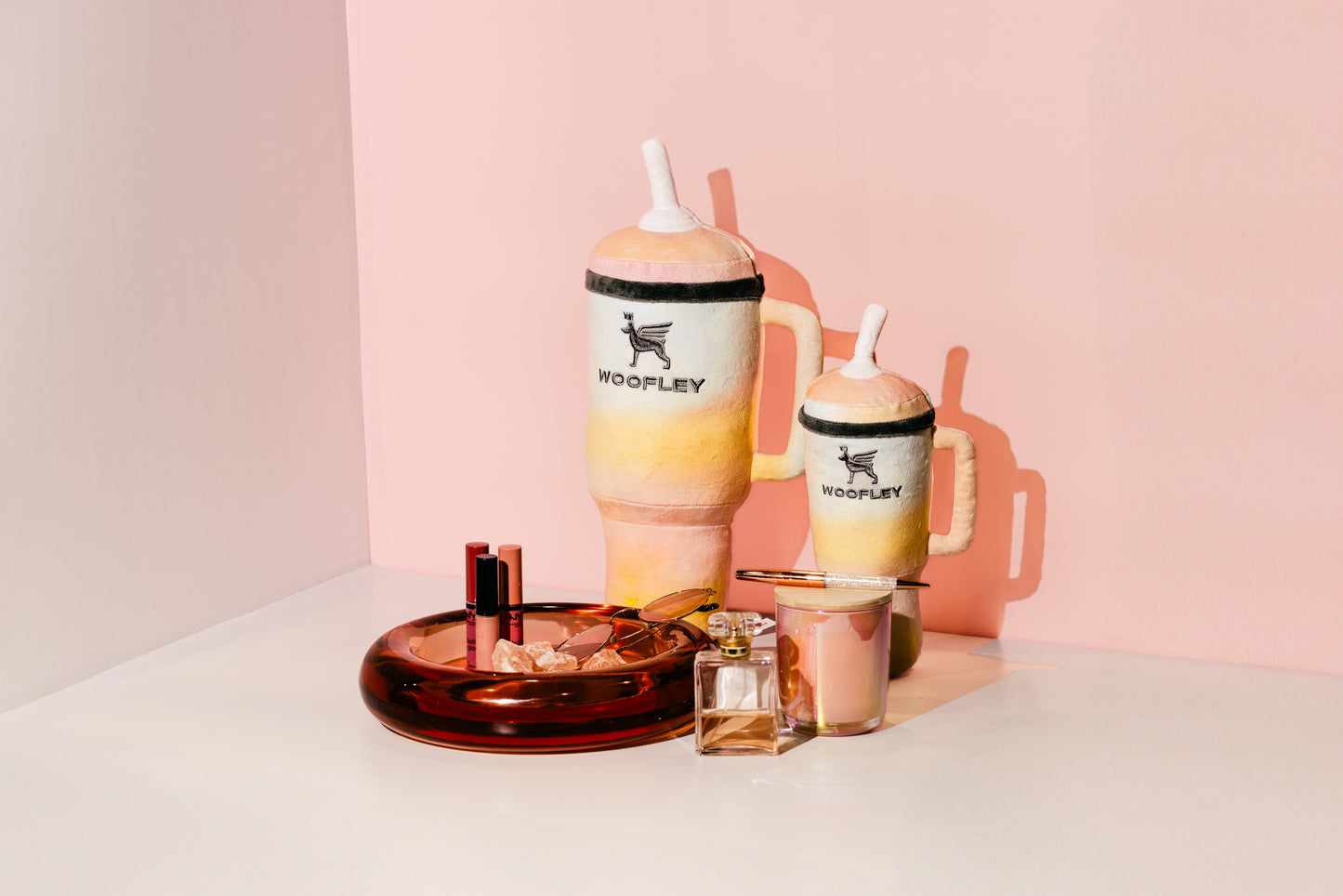 Two colorful tumbler drinks with straws on a pink background