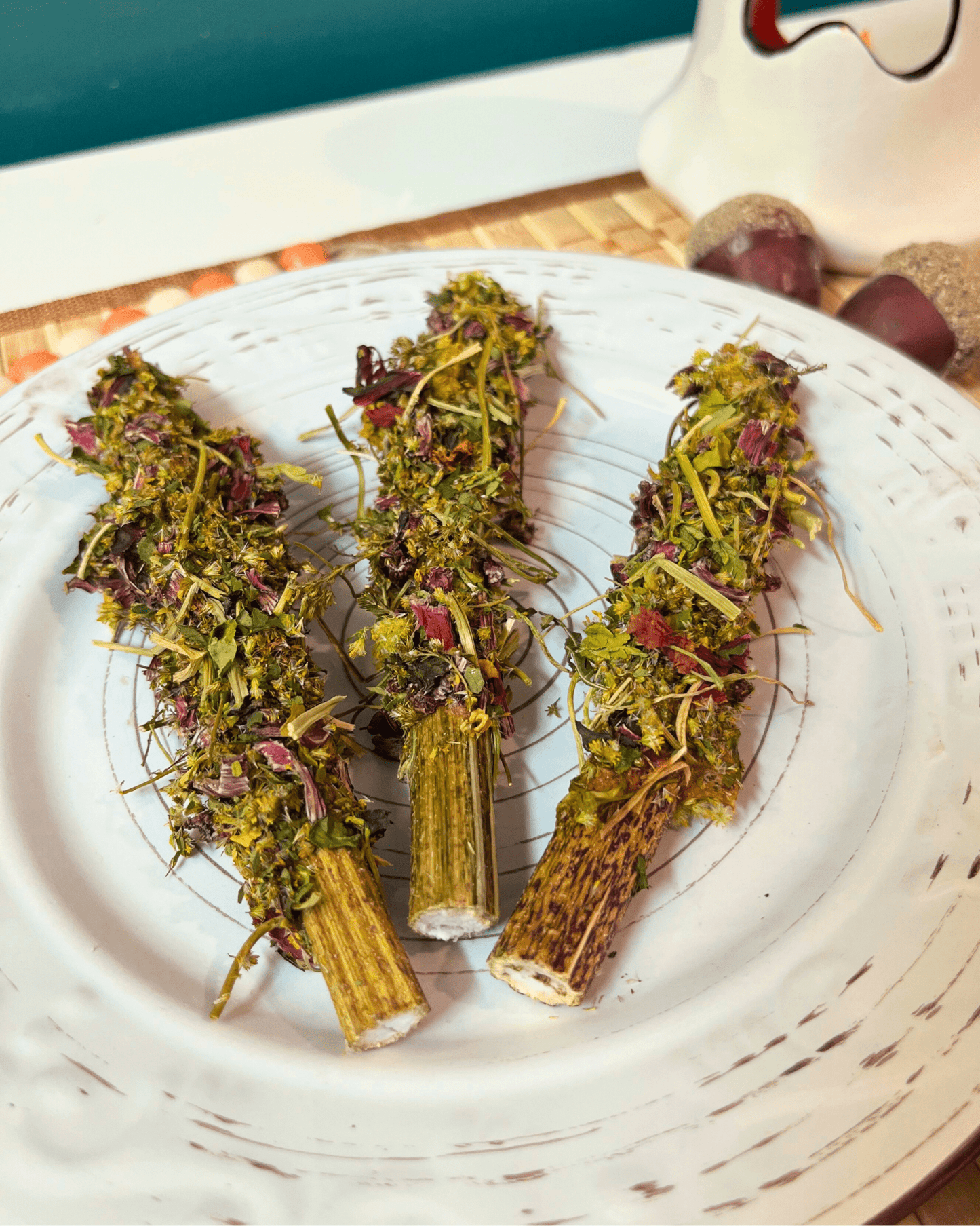 Three dried herb bundles on a white plate with a blurred background