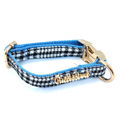Dog collar with blue and black checkered pattern, gold hardware, and visible brand name on a white background
