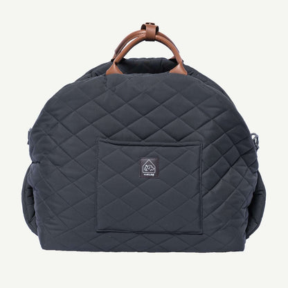 Quilted navy blue backpack with brown handle on a white background