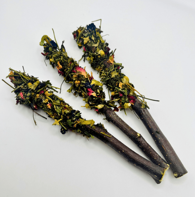 Three dried herb sticks with colorful flowers on a white background