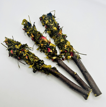 Three dried herb sticks with colorful flowers on a white background