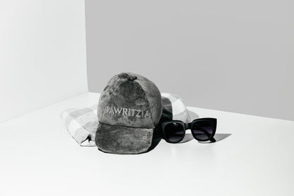 Gray cap with 'Wawrzyniec' branding and black sunglasses on a white surface.