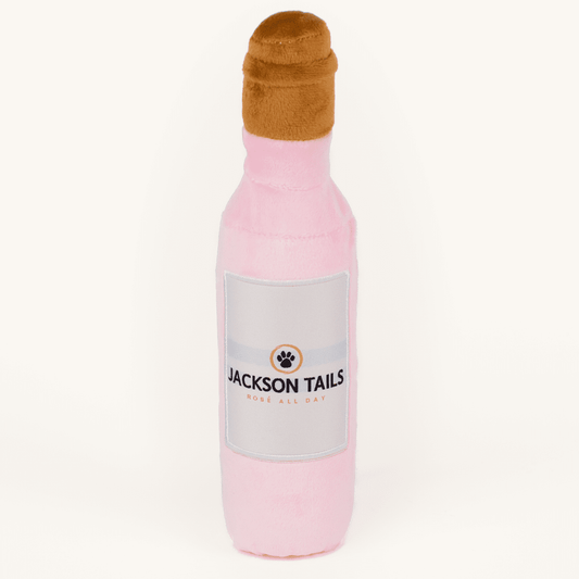Pink bottle-shaped dog toy with a brown cap on a white background, branded 'Jackson Tails'.