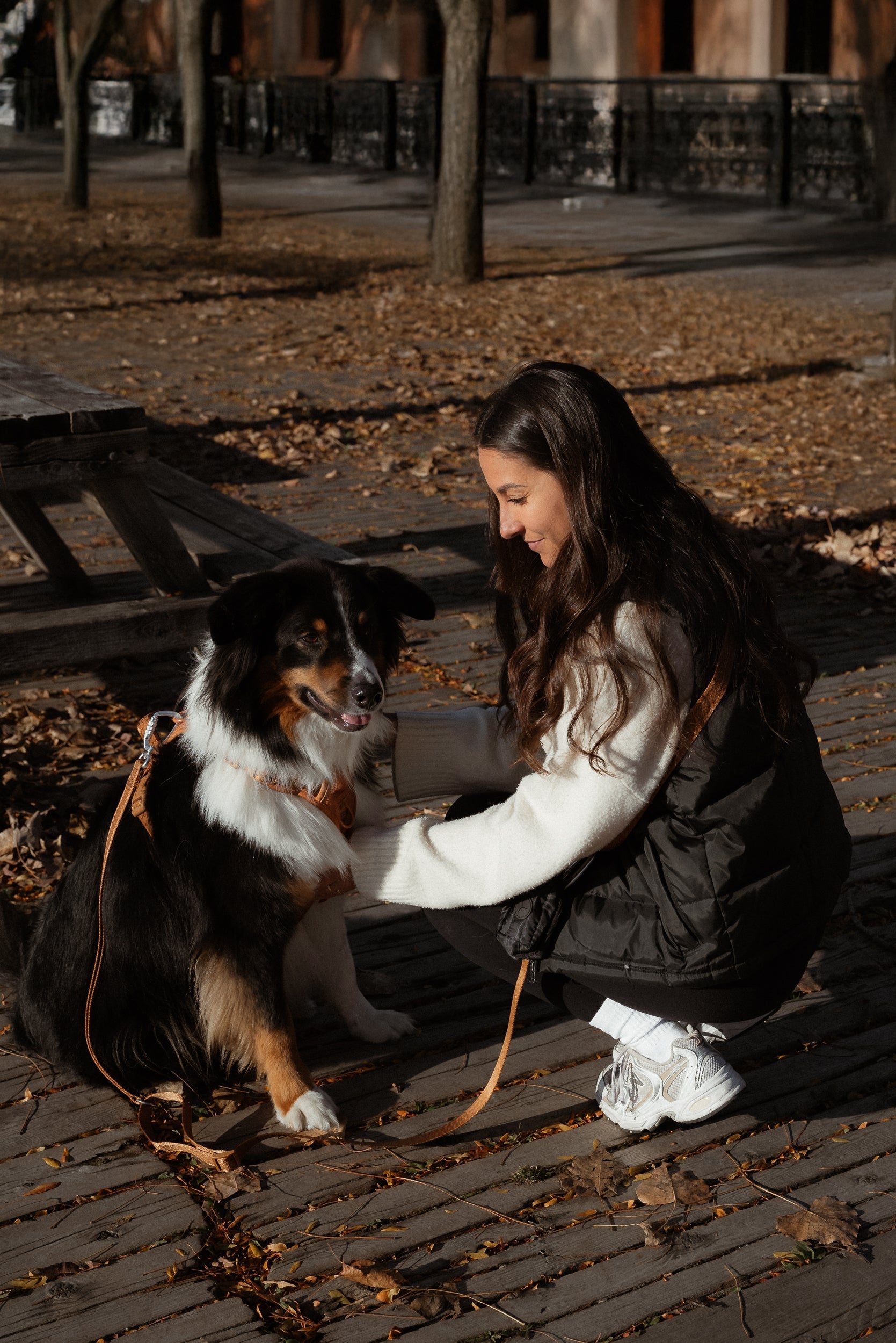 Woman sitting on a wooden bench with a dog in an outdoor setting