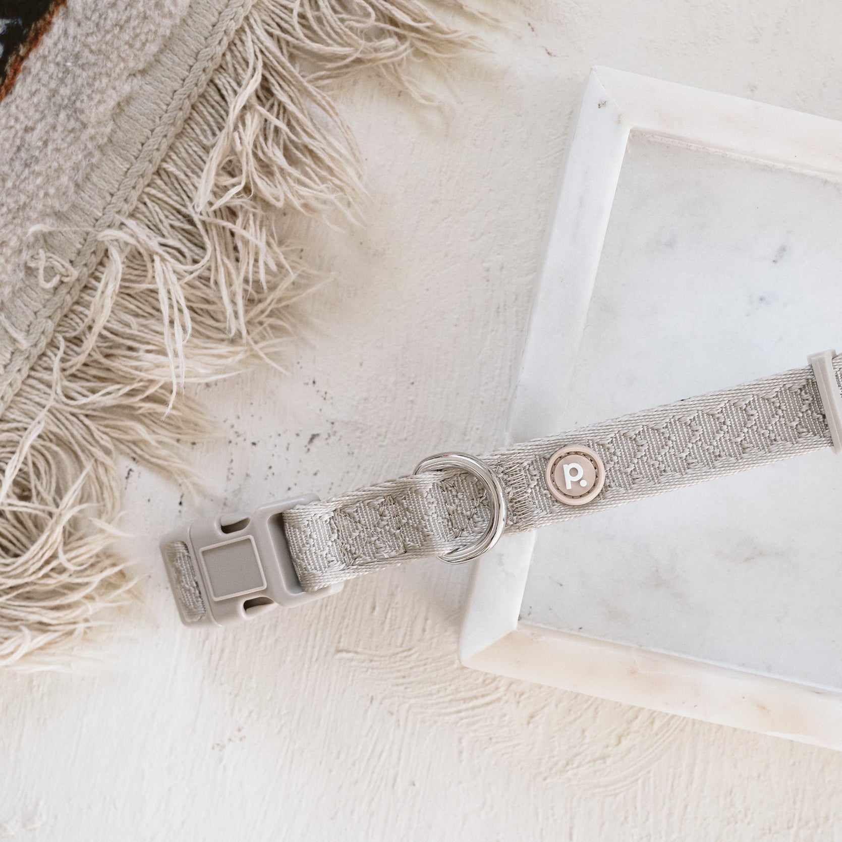 Dog collar on a marble surface with a textured rug in the background