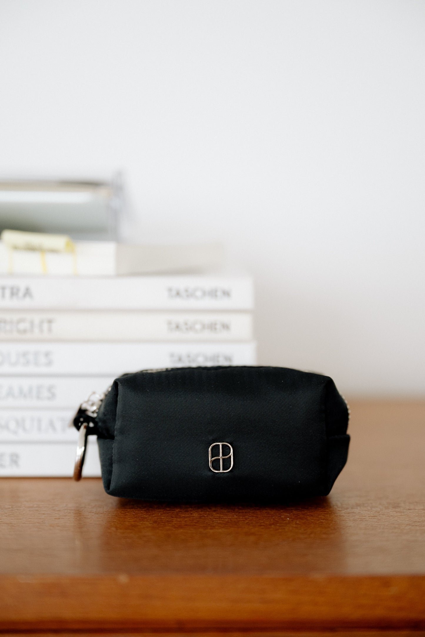Black pouch on a wooden surface with books in the background