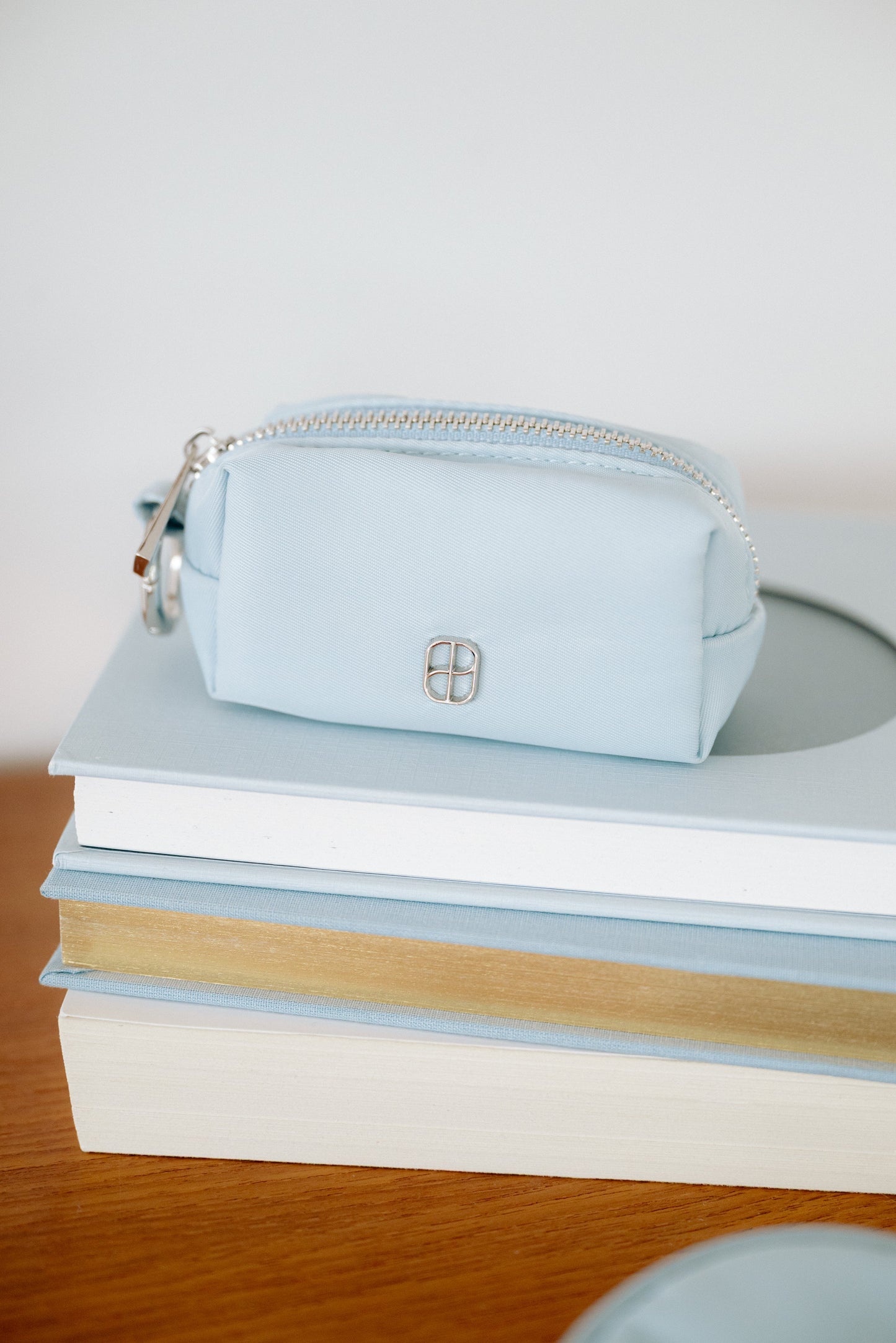Light blue pouch on a stack of books with a white background